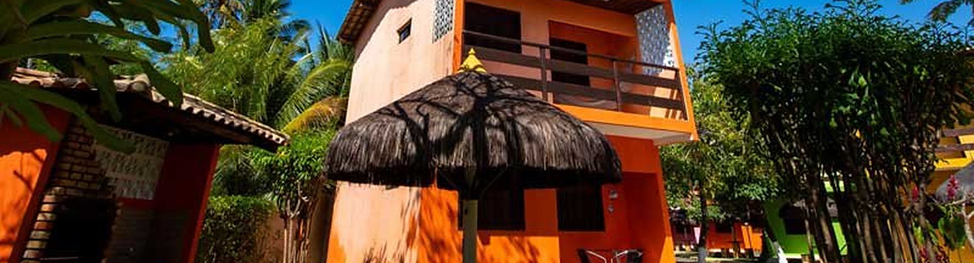 Chalé da pousada com quiosque de palha e jardim