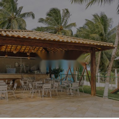 Quiosque coberto com mesas e cadeiras junto ao jardim