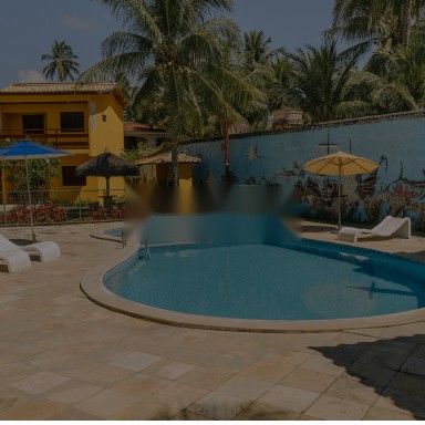 Piscina ao ar livre com o painel marinho e os chalés ao fundo
