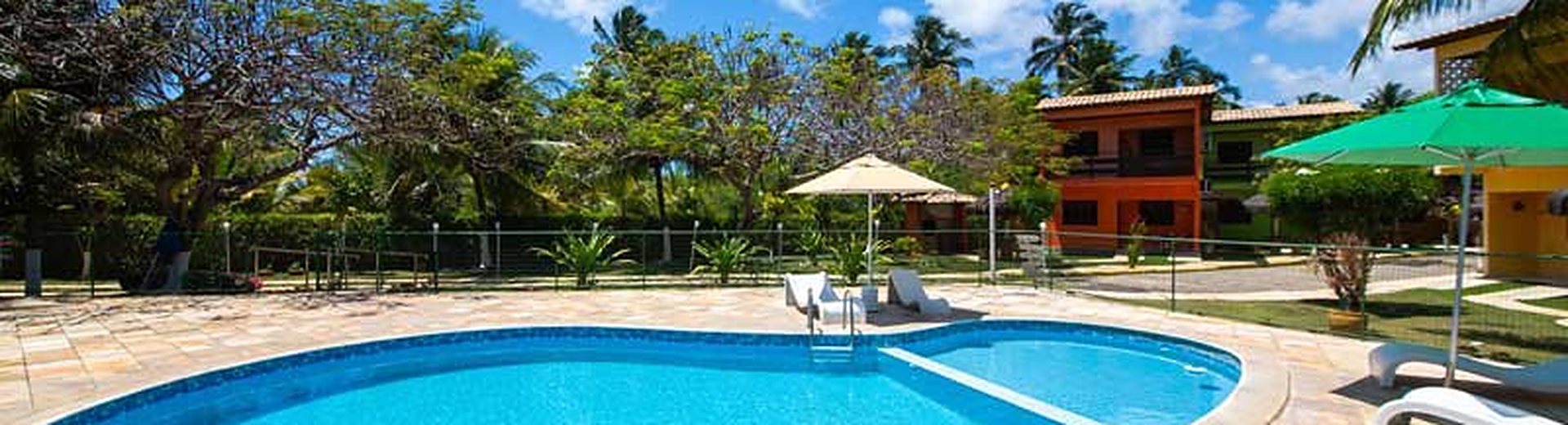 Piscina com espreguiçadeiras e os quiosques ao redor