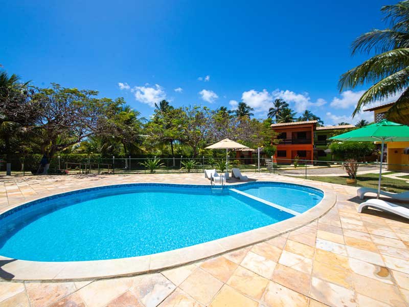 Piscina com espreguiçadeiras e os quiosques ao redor
