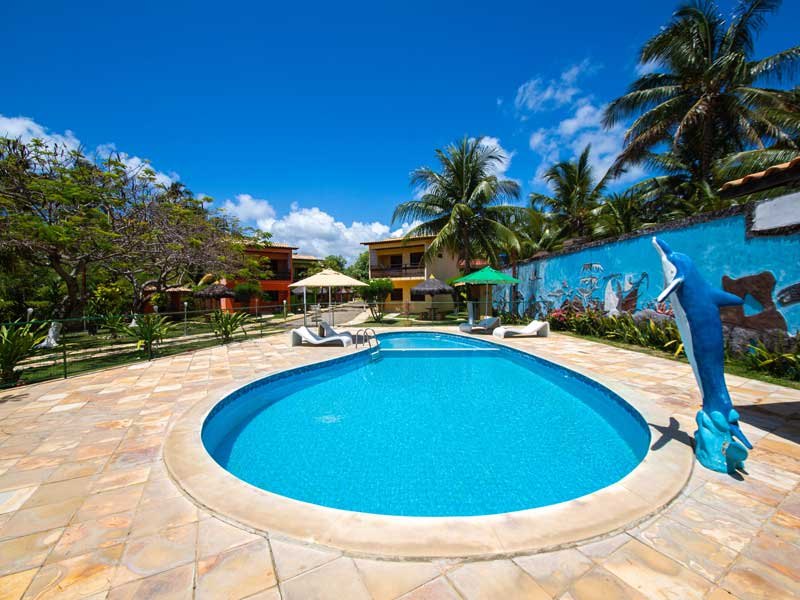 Piscina com espreguiçadeiras e o quiosque ao fundo