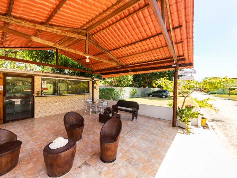 Quiosque coberto com mesas e cadeiras junto ao jardim