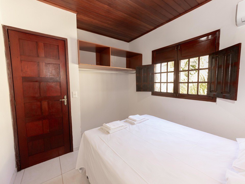 Quarto com cama de casal, toalhas decoradas e janela para o verde